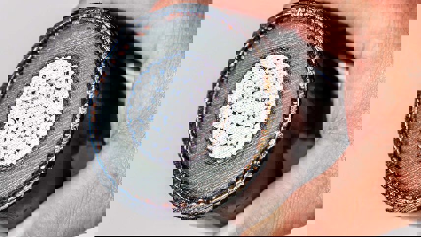 Hand hält den Querschnitt eines Stromkabels mit Leiter, Isolation und Mantel.