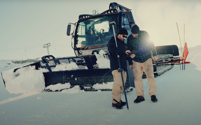 Zwei Männer vor einer Pistenraupe bei der Vorbereitung der Skipiste für die FIS Freestyle WM 2025.
