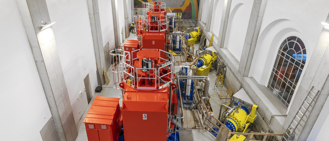 Maschinenhalle mit leuchtend roten und gelben Turbinen – erste Anlage von Repower im Probebetrieb.