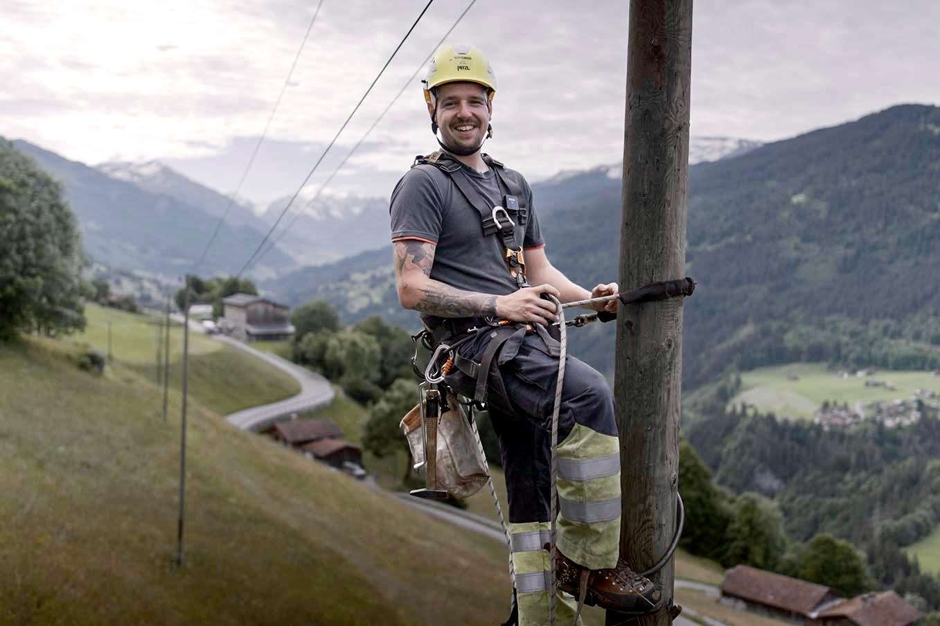 Ein Repower-Netzelektriker auf einem Mast im Prättigau