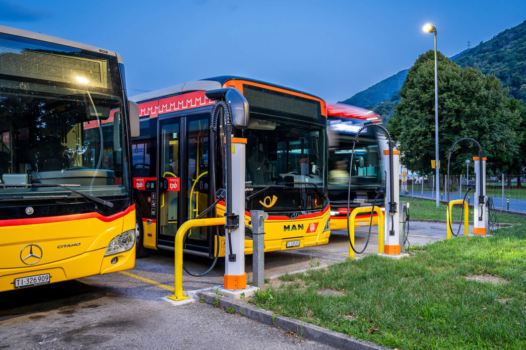 DC-Ladeinfrastruktur im PostAuto Depot Bellinzona mit drei Kempower Satelliten und Postautos, die ihre Batterien aufladen.